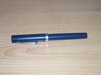 Side view of vintage blue Sheaffer fountain pen with silver band on cap.