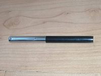 Full view of the vintage black Sheaffer fountain pen placed horizontally on a wood surface showing black barrel and silver-tone cap