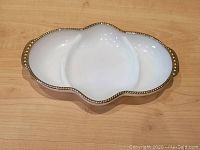 Full top-down view of white milk glass serving dish with gold embossed trim and divided center
