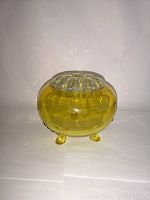 Side/front view of the yellow glass flower frog bowl with clear insert, showing three feet and smooth rounded form.