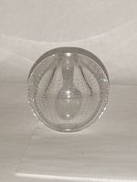 Clear art glass paperweight viewed from the side showing rounded shape with internal bubbles and smooth flat base.
