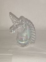 Front angle showing unicorn's horn, face, and body with internal reflections in the glass.