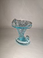 Side angle view of blue Fenton hobnail cornucopia vase highlighting the shape and hobnail pattern.