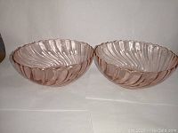 Pair of pink Arcoroc France glass serving bowls placed side by side on a plain white surface, showing overall shape, size, and color.