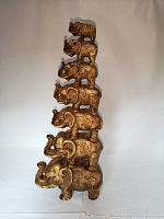 Front view of the full six-elephant vertical stack sculpture showing the entire piece and detail of texture and finish