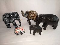 Photo showing all five wood elephant figurines together on a white background, highlighting different sizes, colors, and decorations.