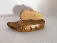 Opened wooden shoe-shaped box showing interior compartment and hinge mechanism