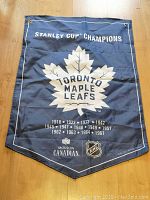 Front view of the blue fabric banner spread on wooden floor, showing the team logo and text.