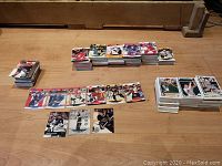 Multiple stacks of hockey and baseball cards spread on the floor showing a large collection.