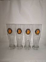 Front view of all four clear pint glasses displaying the Shock Top Belgian White logo on each.