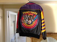 Rear view of black leather jacket with multicolor Looney Tunes appliqué and concentric rings of purple, red, orange and yellow.