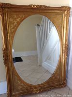 Full front view of mirror leaning against wall showing oval bevelled mirror plate and overall frame