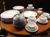Overview of entire dish service arranged on table showing all plates, cups, saucers, cream jug and sugar bowl