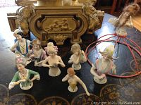 Ten porcelain half dolls arranged on a round table top.