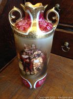 Front view of the antique RS Germany gilt cabinet vase showing detailed painted figures and ornate gold handles.