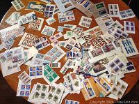 Overview of table covered with various mint Canadian stamps in original packaging and loose sheetlets
