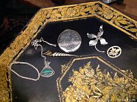 Photo showing entire lot on a decorative black and gold tray, including chain bracelet, pendant, compact, butterfly brooch and crystal brooch.