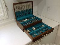 Full open box showing all compartments filled with flatware pieces organized by type and size.