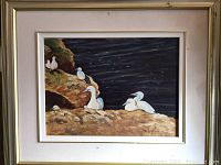 Framed oil painting showing egrets on cliff with dark blue background.