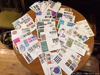 Overview of entire lot spread on round table showing dozens of First Day Cover envelopes with varied stamps and cancellations