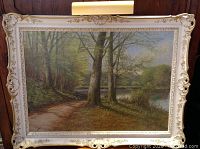 Front view of framed landscape oil painting showing river, path and trees