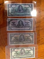 Front faces of four notes in protective sleeves