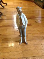 Full view of porcelain figurine standing on wooden floor showing front and side profile