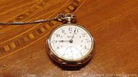 Pocket watch face and attached chain on wooden surface