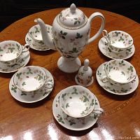 Overall set arranged on wood table, six cups and saucers, teapot with lid and sugar shaker.