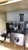 Full view of Decen food processor with box, showing main unit with control dial and processing bowl attached, some attachments beside it
