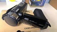 Photo of the 4K Ultra HD camcorder with lens cover and flipped out LCD screen showing product branding
