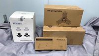Lot contents with three boxes labeled RunNly ceiling light, LED garage lights and wireless motion sensor LED light.