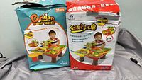 Two box packages featuring the Chuan brand sand and water table toys with a child's image on each box, showing the stand-up activity table for kids.
