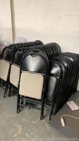 Stacks of black metal folding chairs with padded white seats shown from different angles.