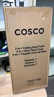 Original cardboard packaging box for the Cosco 2 in 1 Folding Hand Truck with branding and product details visible.