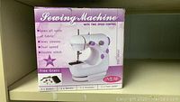 Box front showing sewing machine image and features including dual speed, double stitch, and included accessories.