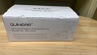 Closed box view of Quinear Air Compression Therapy Device Model QN-021A showing product branding and model number on packaging.