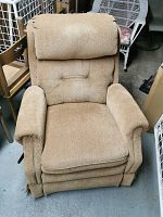 Front view of the upholstered reclining armchair showing the padded armrests, cushioned seat and headrest in light brown fabric.