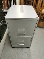 Front view of the metal filing cabinet showing two drawers with handles and casters underneath.