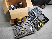 Overview of two cardboard boxes and three plastic tool cases on floor
