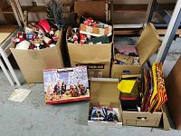 Boxes filled with assorted Christmas ornaments and decorations including figurines, gift bags, and a nativity set box.