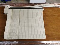 Full view of beige Boston paper cutter with cutting arm and measurement grid surface.