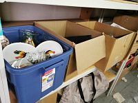 Blue plastic bin with plates featuring rooster designs and various vases inside