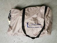 Closed beige nylon carry case with black straps and Aerobed logo printed in blue, containing the air mattress inside.