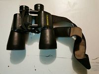 Full view of black Bushnell binoculars showing body, lenses, and attached shoulder strap.