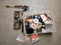Overview of all fishing equipment including rods with reels, spools of line, floats, and tackle box