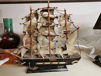 Full side view of the wooden model sailing ship showing its three masts, sails, hull, and stand.