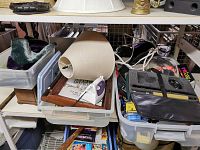 Various household and decorative items including a lamp base with shade, picture frames, and stored in plastic bins on shelving.