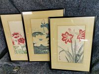 Set of three framed oriental watercolours depicting flowers, showing overall size and presentation with three artworks side by side against a black background, a wristwatch for scale.