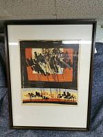 Framed serigraph print featuring abstract prairie forms in orange, black, cream, and light blue with glass reflection.